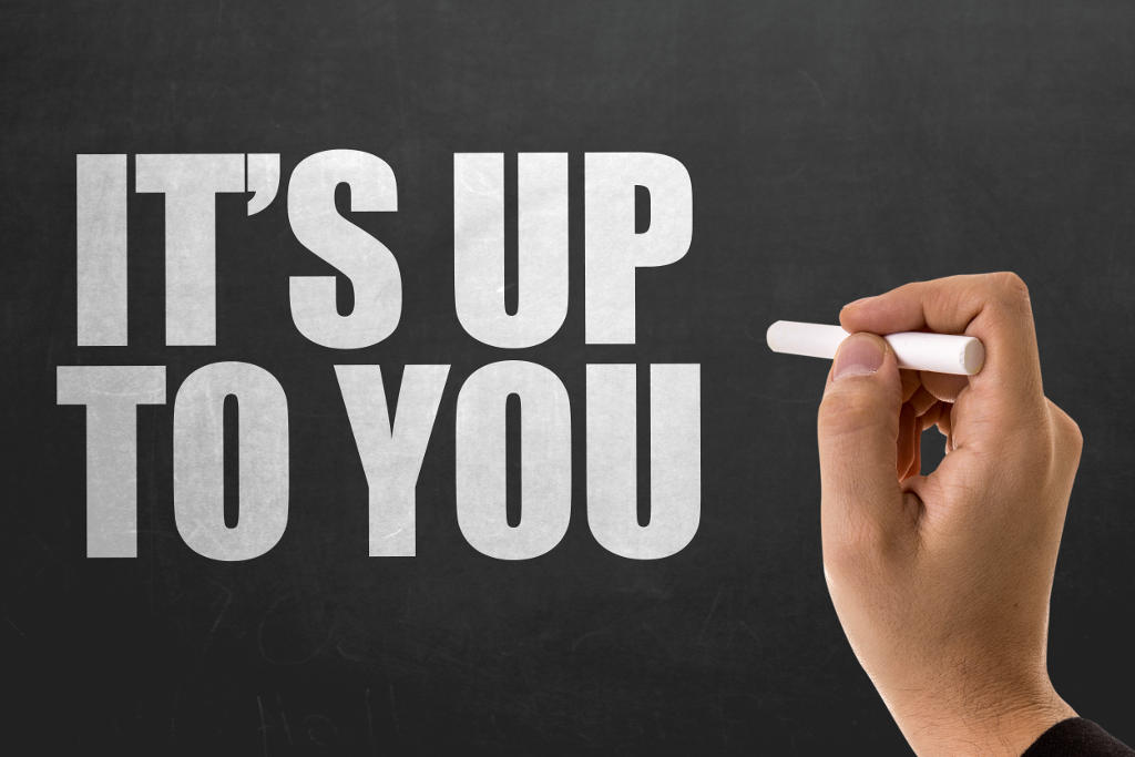 A hand holding a piece of chalk writes ITS UP TO YOU in large white...